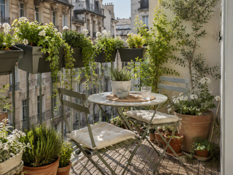 Idée d’aménagement pour balcon urbain avec jardinières suspendues, fleurs blanches, table bistro et plantes faciles à entretenir.