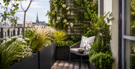 Aménagement d’un petit balcon à Genève avec bacs anthracite, treillis végétalisé, plantes grimpantes et coin détente intimiste.